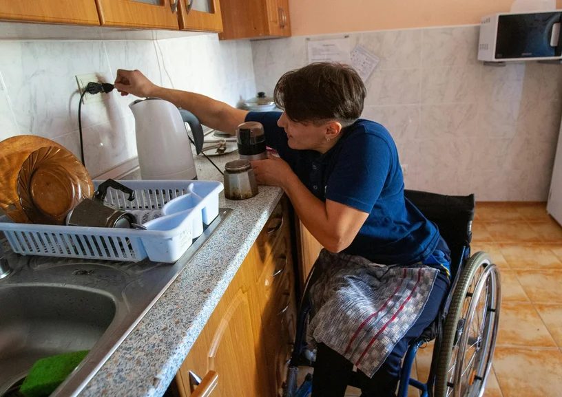 Une personne en fauteuil roulant prépare du café dans sa cuisine